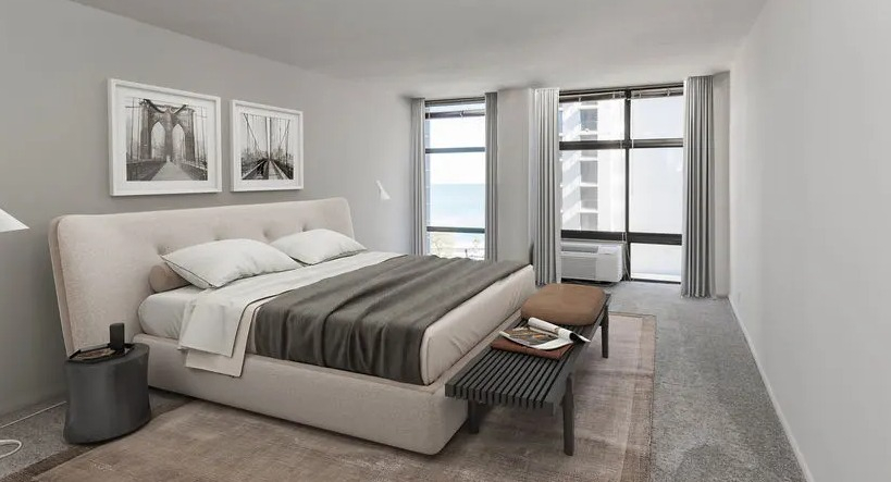 Spacious bedroom with large windows, lake glimpse, neutral decor, and carpeted flooring at 65 East Scott apartments in Chicago