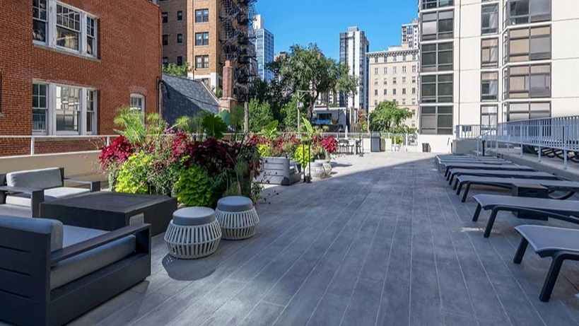 Expansive outdoor lounge with seating areas, planters, and sun chairs on the terrace at 65 East Scott apartments in Chicago
