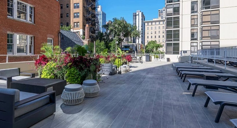 Expansive outdoor lounge with seating areas, planters, and sun chairs on the terrace at 65 East Scott apartments in Chicago