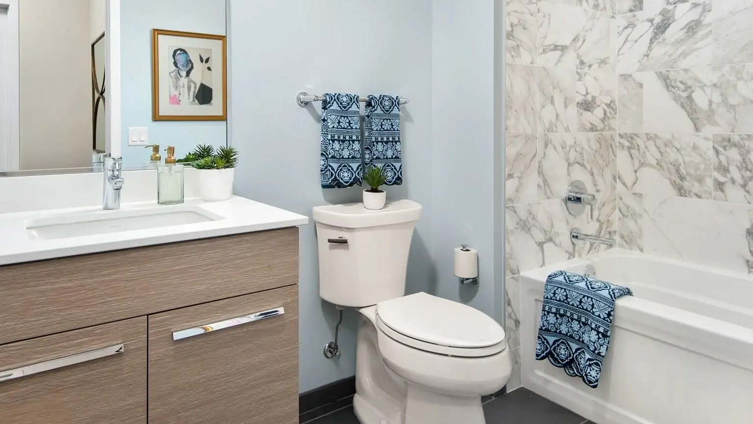 Contemporary bathroom at 727 West Madison in Chicago with quartz vanity, light wood cabinets, and marble tile shower-tub combo