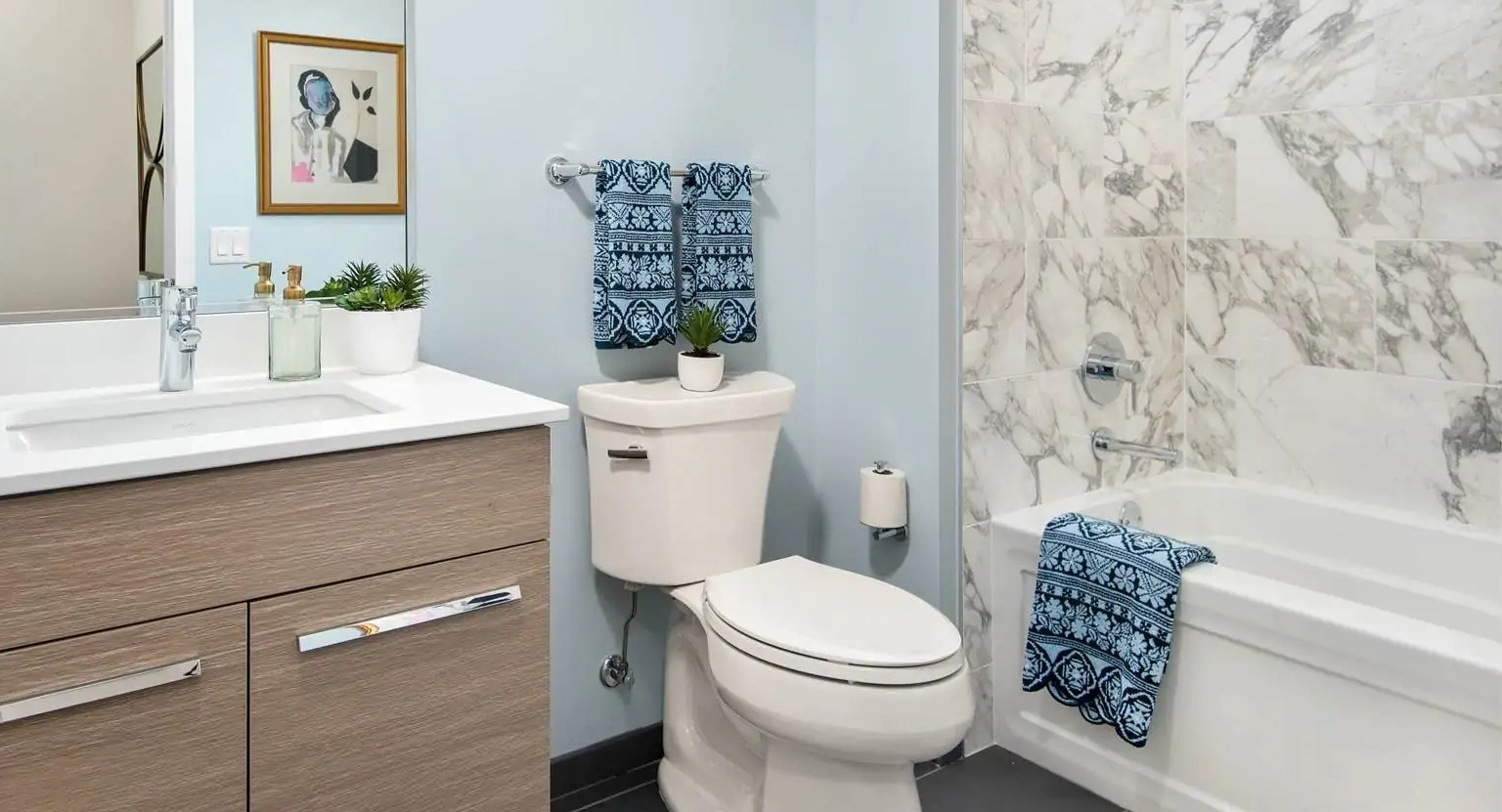 Contemporary bathroom at 727 West Madison in Chicago with quartz vanity, light wood cabinets, and marble tile shower-tub combo