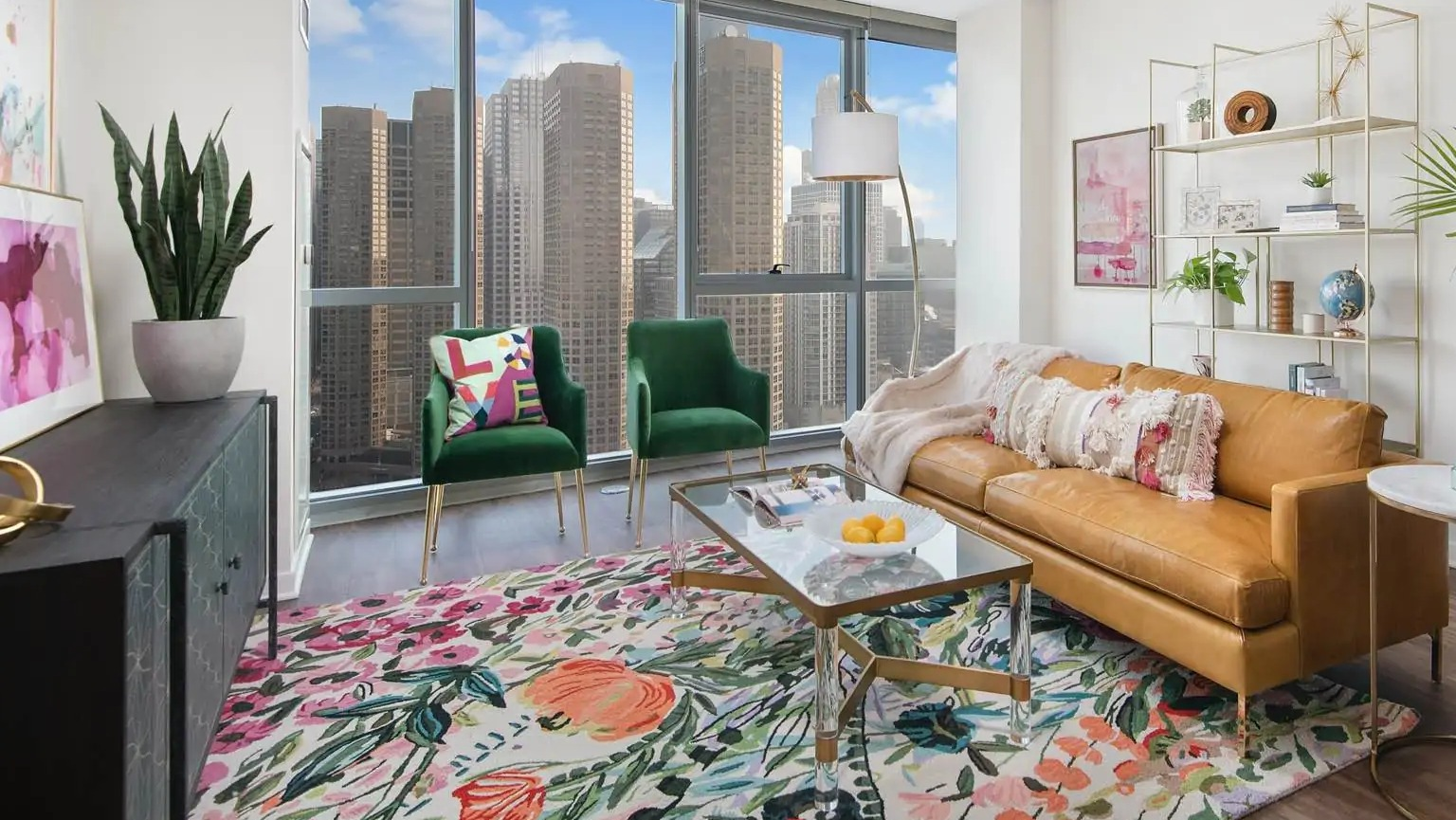 Bright living room at 727 West Madison in Chicago with leather sofa, green chairs, floral rug, and tall windows overlooking the skyline