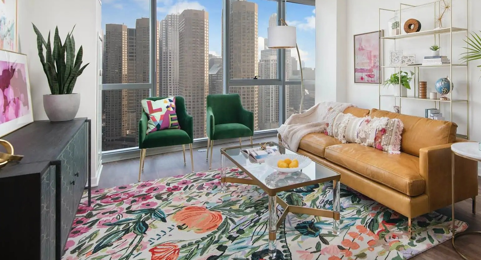 Bright living room at 727 West Madison in Chicago with leather sofa, green chairs, floral rug, and tall windows overlooking the skyline