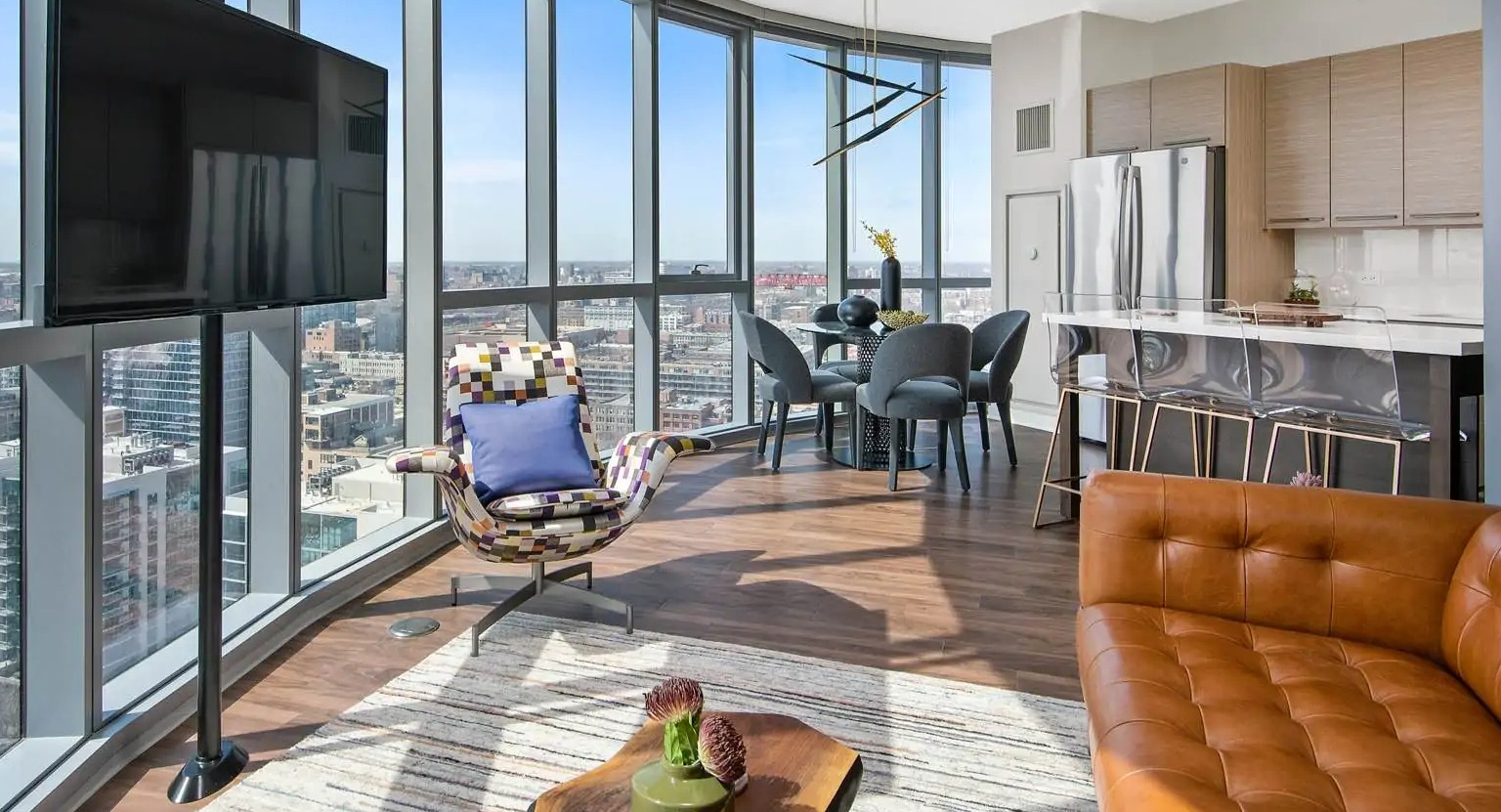 Corner living room at 727 West Madison in Chicago showcasing curved window walls, dining area, and open kitchen with dramatic city views