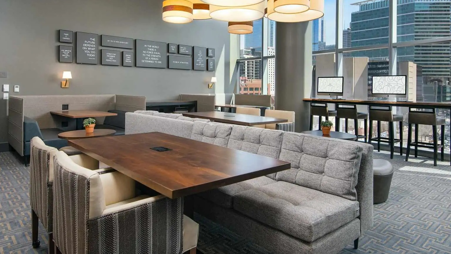 Coworking lounge at 727 West Madison in Chicago with booth seating, large tables, computer stations, and window walls overlooking downtown
