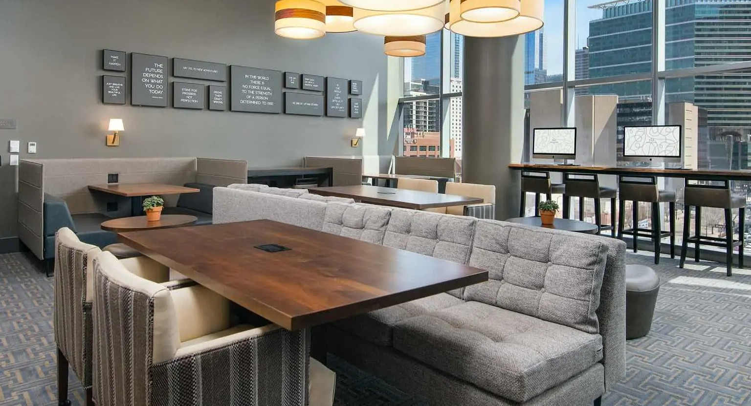 Coworking lounge at 727 West Madison in Chicago with booth seating, large tables, computer stations, and window walls overlooking downtown