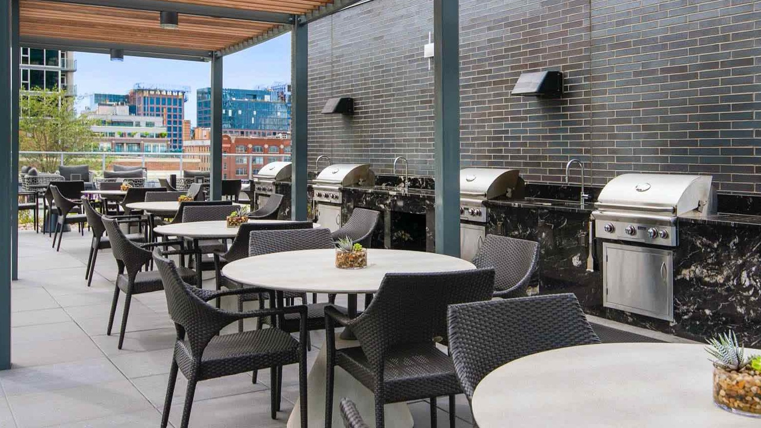 Outdoor grilling terrace at 727 West Madison in Chicago with pergola shade, stainless grills, café seating, and city views for summer dining