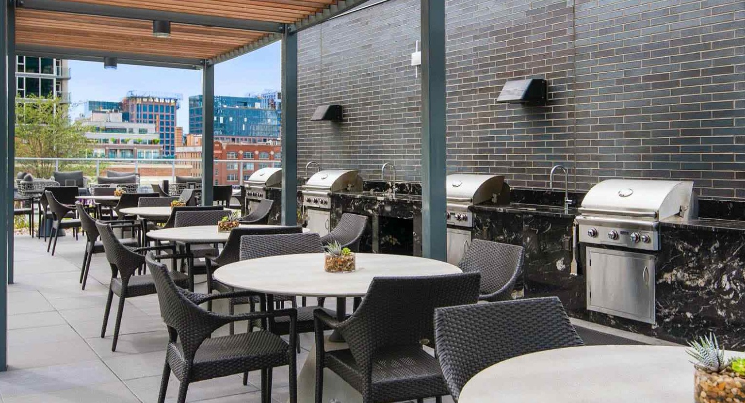 Outdoor grilling terrace at 727 West Madison in Chicago with pergola shade, stainless grills, café seating, and city views for summer dining