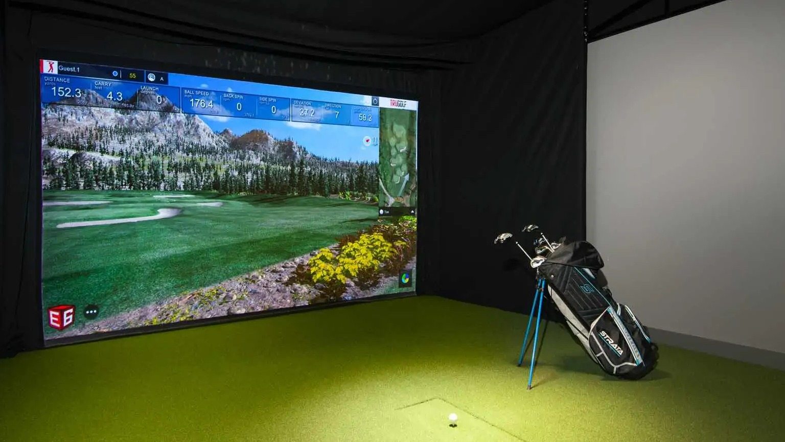 Indoor golf simulator at 727 West Madison in Chicago, featuring a large projection screen, green turf mat, and clubs for year-round practice