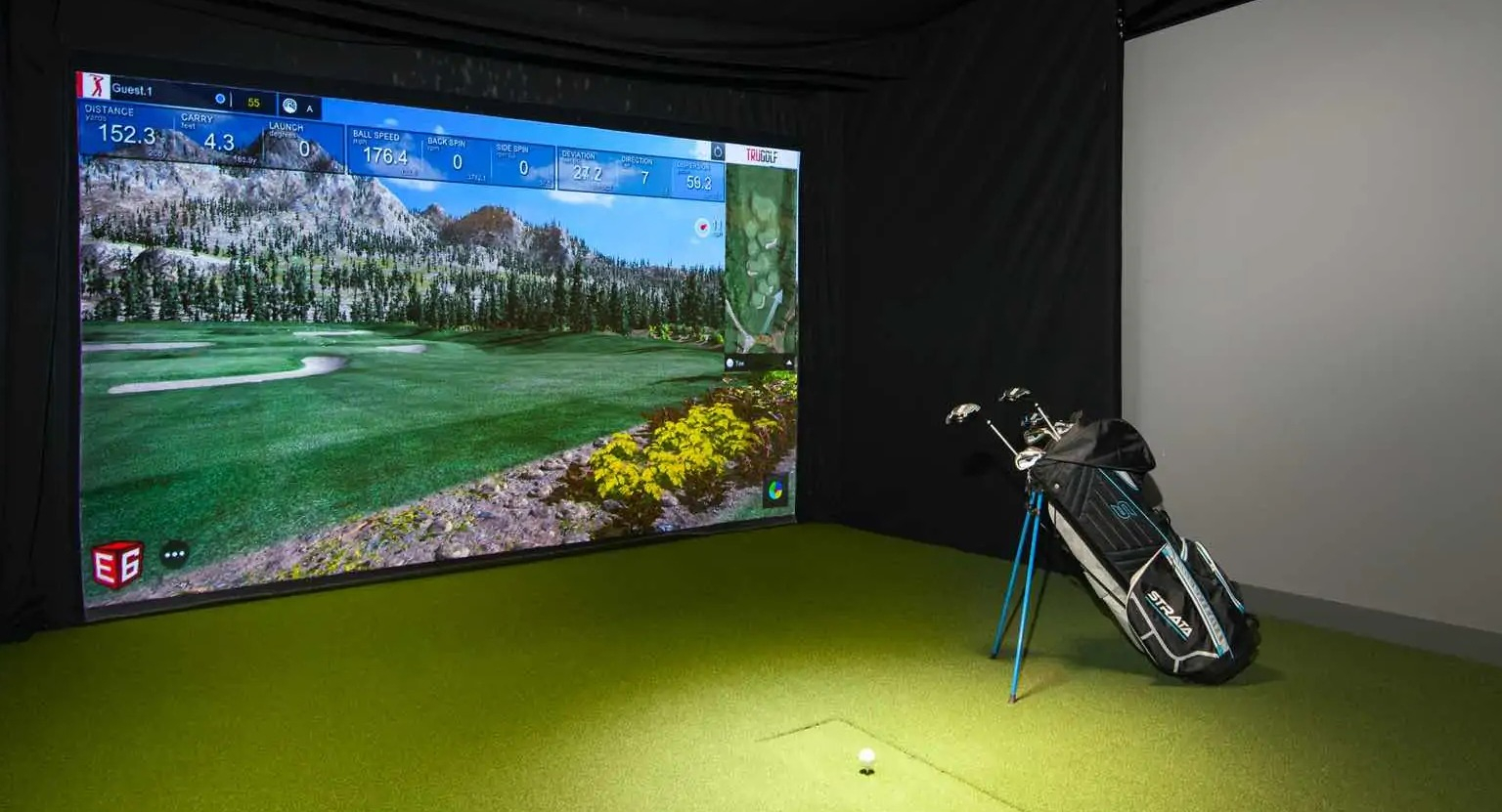 Indoor golf simulator at 727 West Madison in Chicago, featuring a large projection screen, green turf mat, and clubs for year-round practice