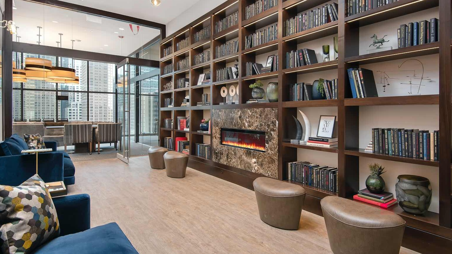 Quiet library lounge at 727 West Madison in Chicago, lined with floor-to-ceiling bookshelves, a modern fireplace, and cozy seating