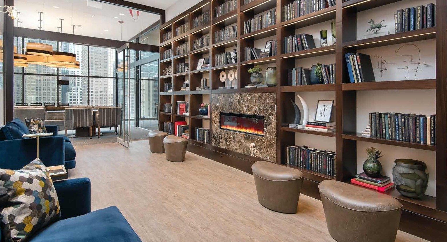 Quiet library lounge at 727 West Madison in Chicago, lined with floor-to-ceiling bookshelves, a modern fireplace, and cozy seating