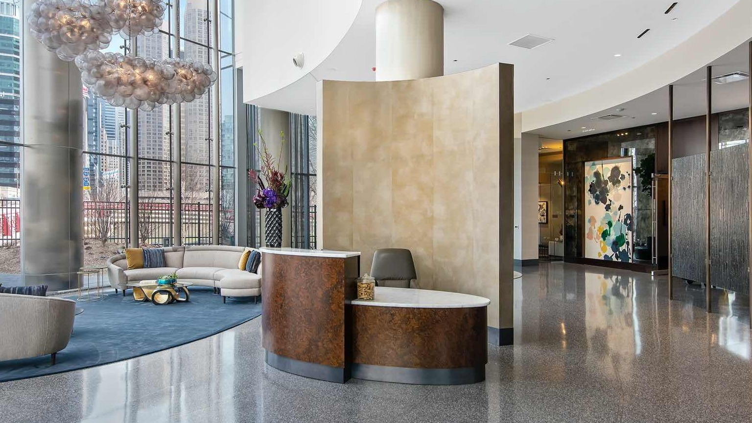 Sophisticated lobby at 727 West Madison in Chicago, with sculptural lighting, curved glass walls, stylish seating areas, and a sleek reception desk