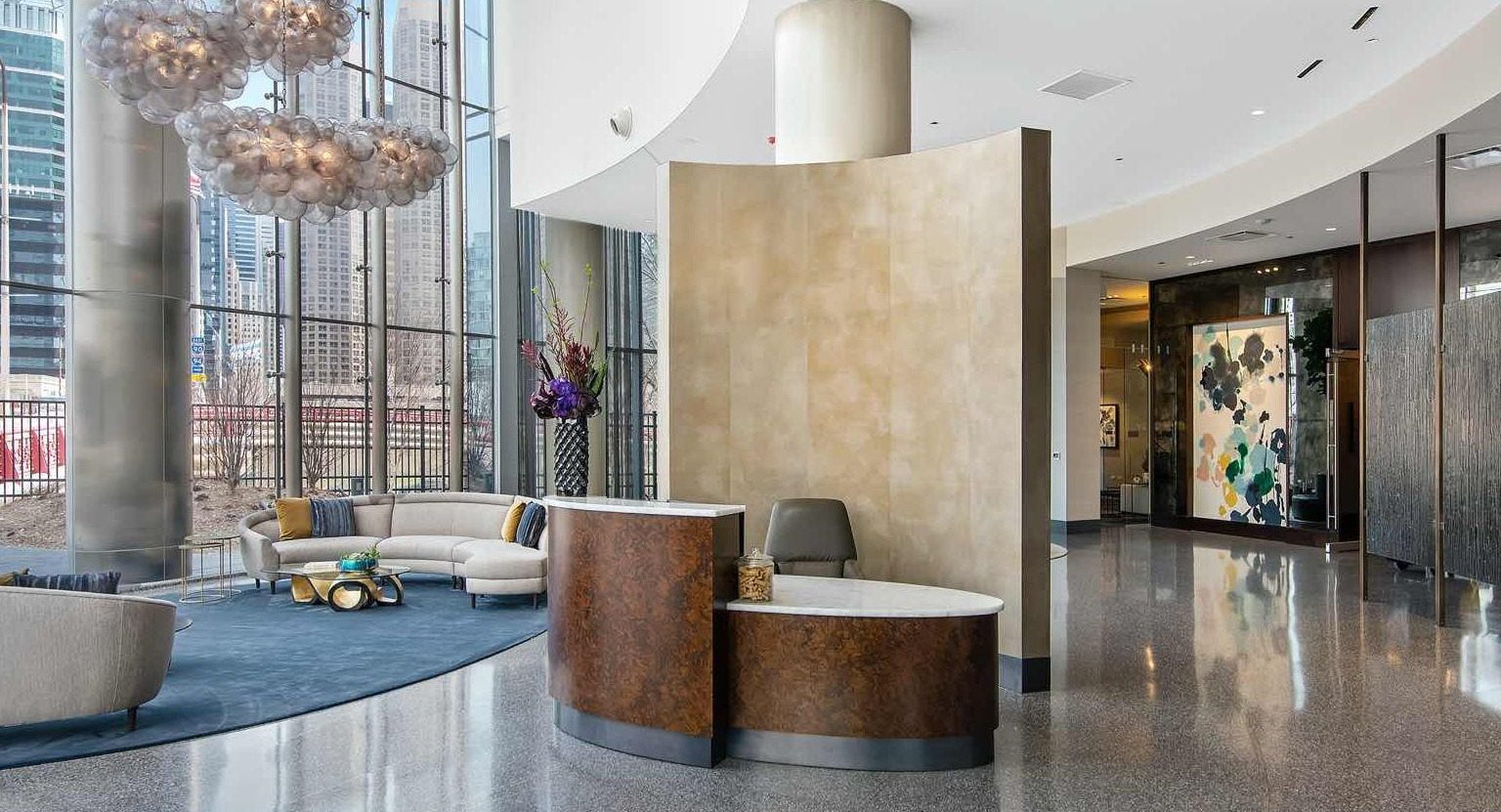 Sophisticated lobby at 727 West Madison in Chicago, with sculptural lighting, curved glass walls, stylish seating areas, and a sleek reception desk