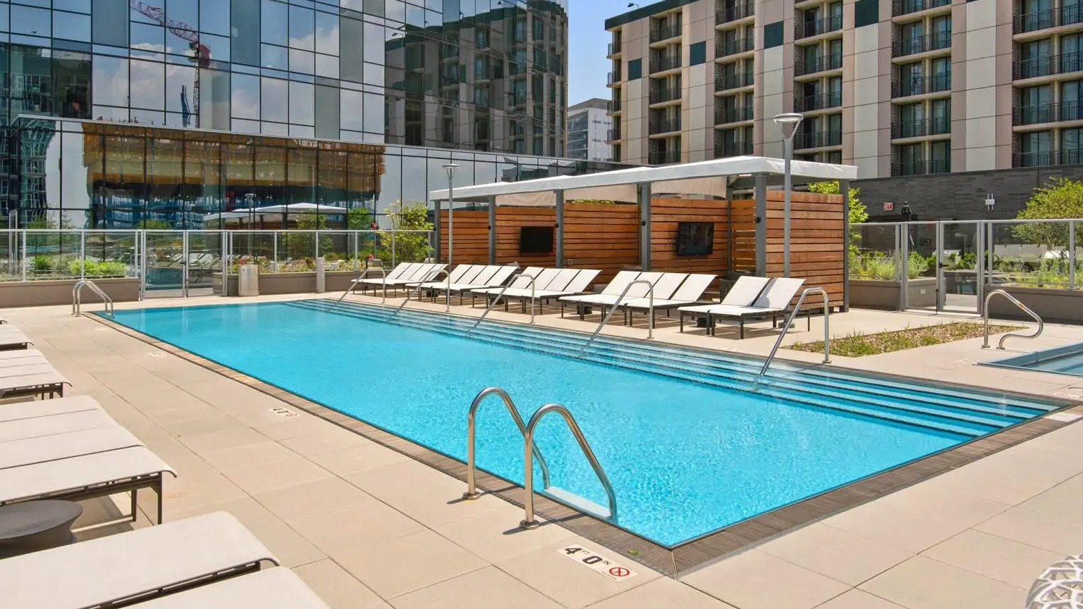 Resort-style outdoor pool at 727 West Madison in Chicago with sundeck loungers, cabanas, and a glass-tower backdrop in the West Loop