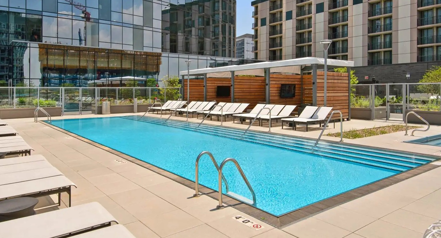 Resort-style outdoor pool at 727 West Madison in Chicago with sundeck loungers, cabanas, and a glass-tower backdrop in the West Loop
