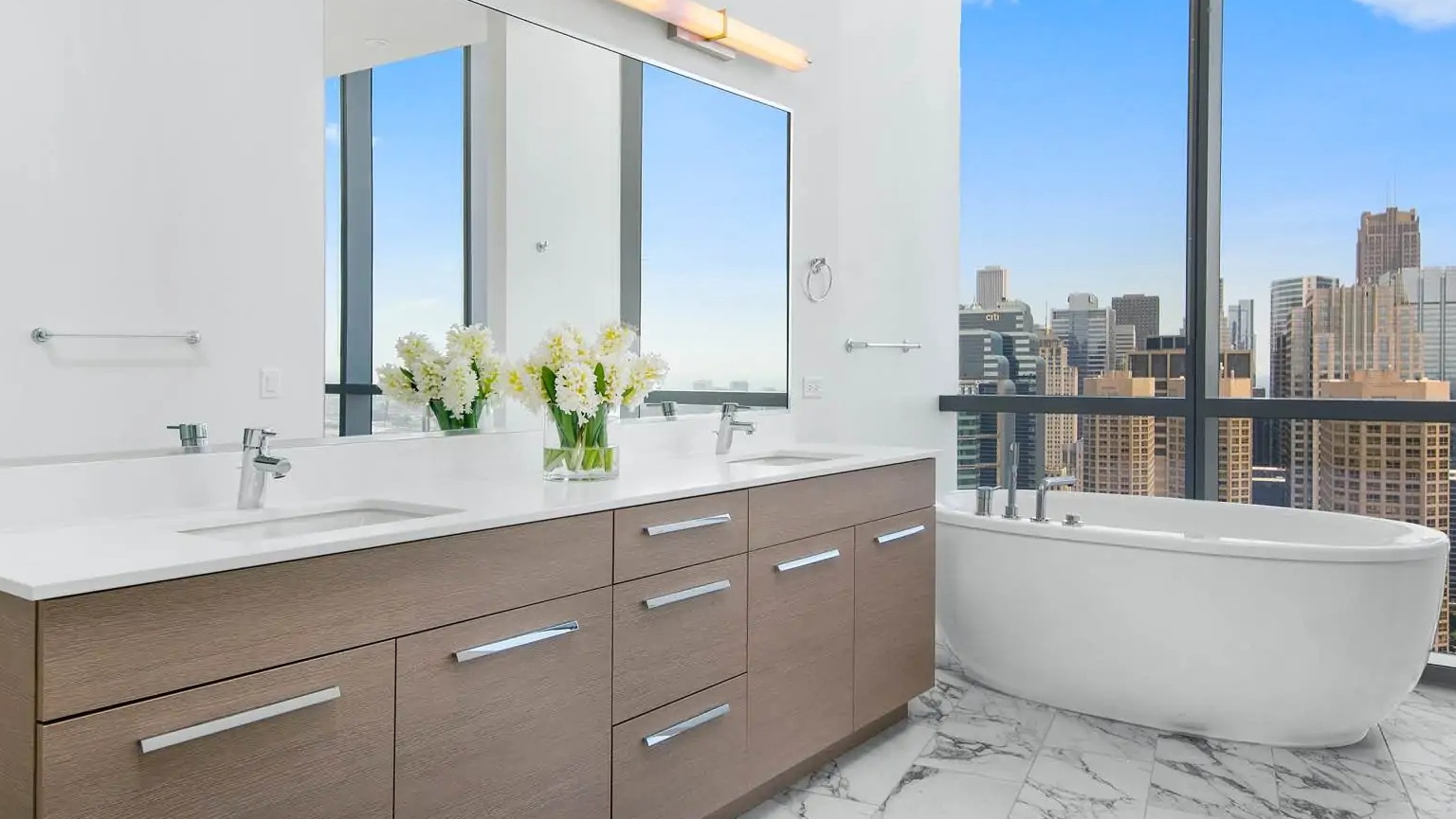 Penthouse bathroom at 727 West Madison in Chicago with double vanity, marble floors, and a freestanding soaking tub beside large windows