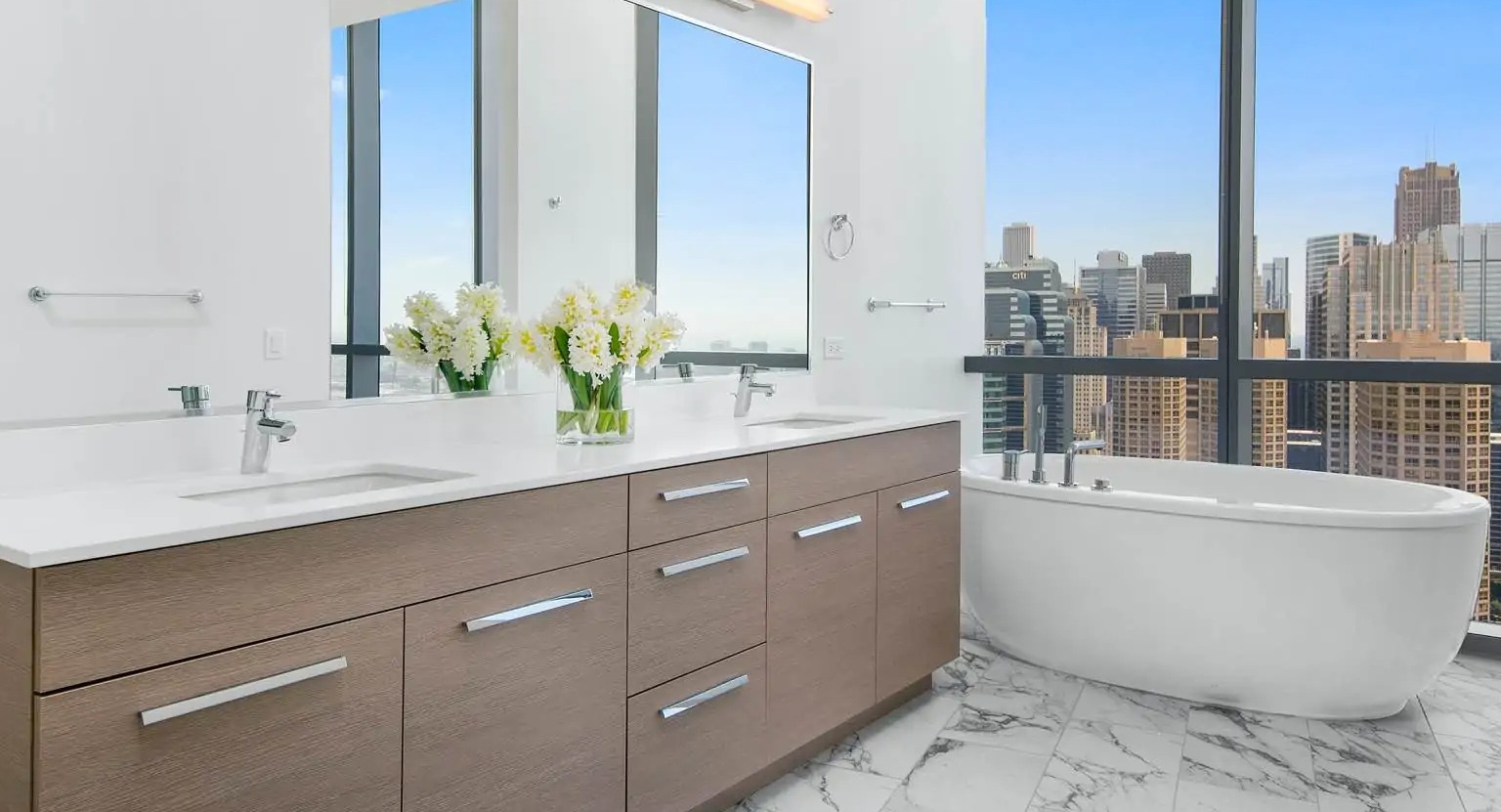 Penthouse bathroom at 727 West Madison in Chicago with double vanity, marble floors, and a freestanding soaking tub beside large windows