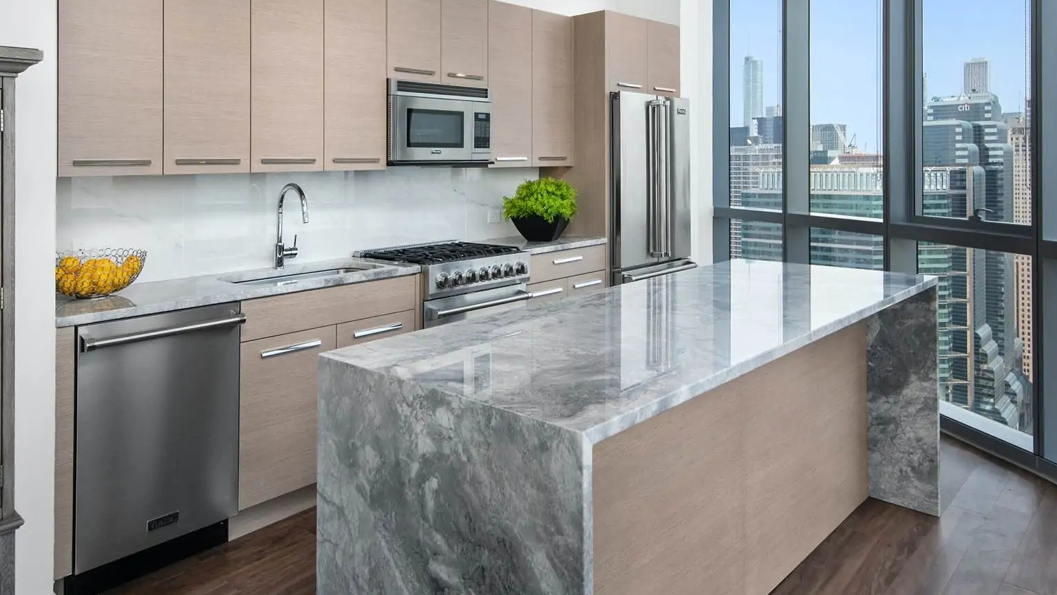 Penthouse kitchen at 727 West Madison in Chicago with premium appliances, light wood cabinets, and a dramatic marble waterfall island