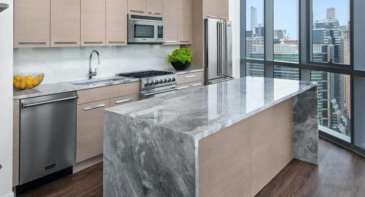 Penthouse kitchen at 727 West Madison in Chicago with premium appliances, light wood cabinets, and a dramatic marble waterfall island
