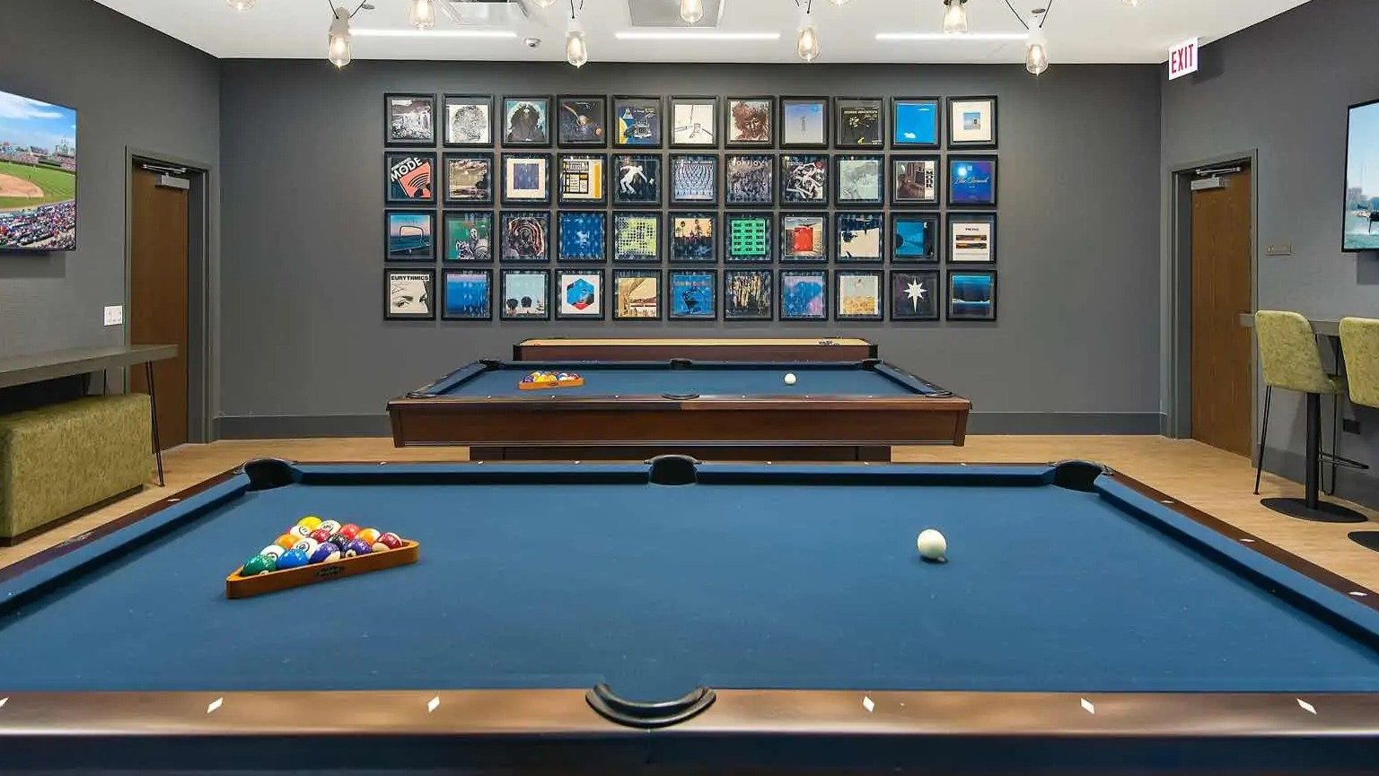 Resident billiards lounge at 727 West Madison in Chicago, with two blue felt pool tables, gallery wall art, and casual seating under pendant lights