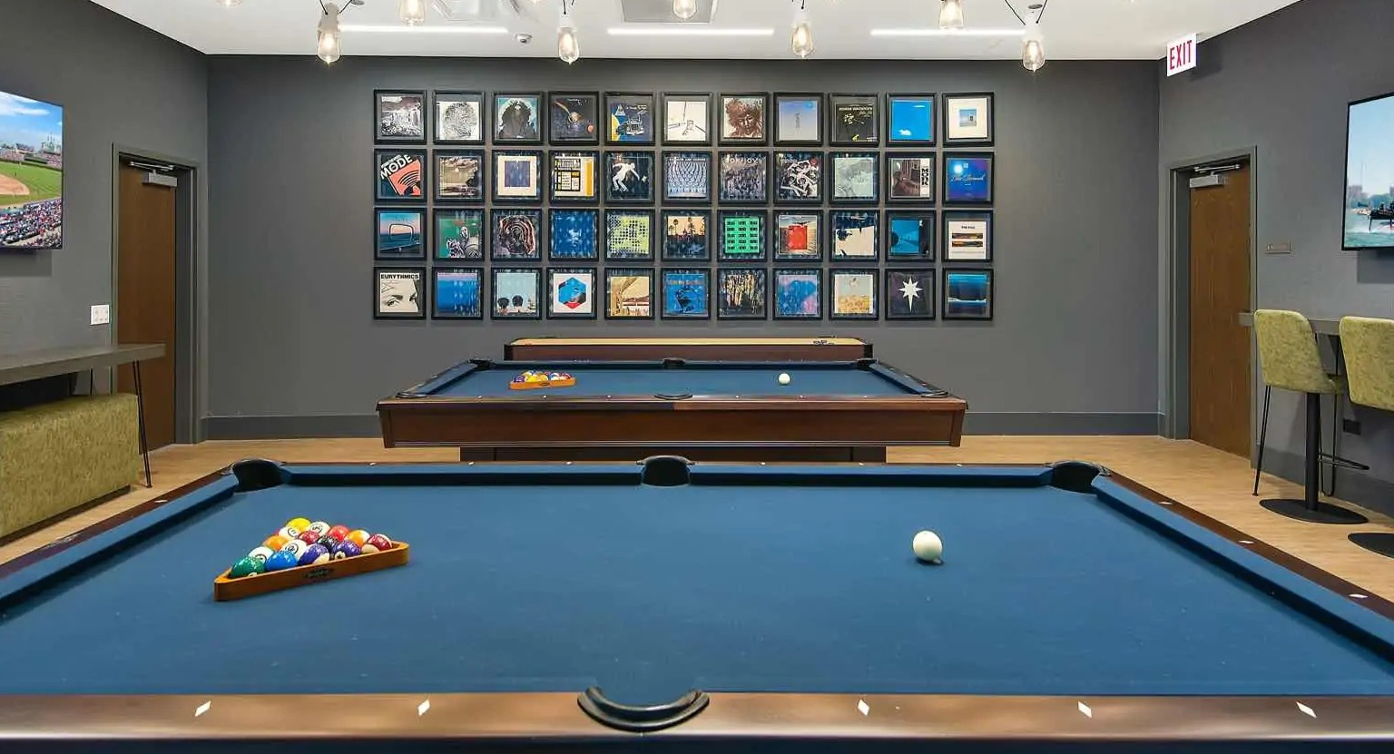 Resident billiards lounge at 727 West Madison in Chicago, with two blue felt pool tables, gallery wall art, and casual seating under pendant lights
