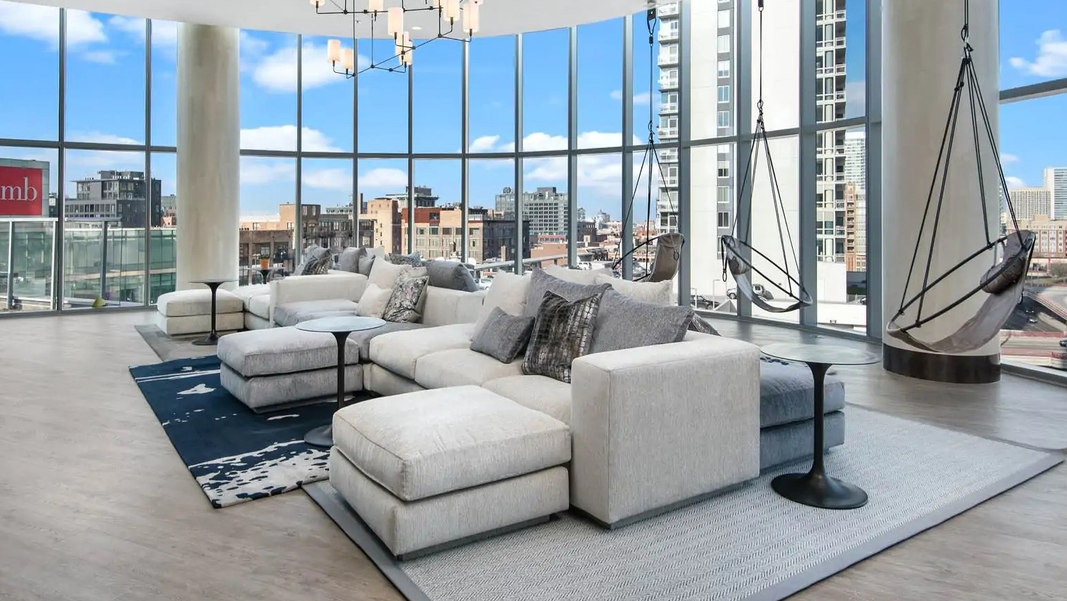 TV lounge at 727 West Madison in Chicago with sectional sofas, hanging swing chairs, floor-to-ceiling windows, and skyline views