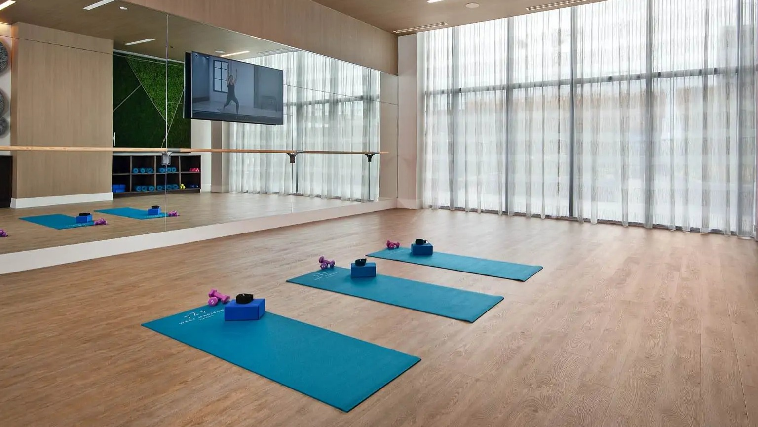 Bright yoga studio at 727 West Madison in Chicago with mirrored wall, barre, wood flooring, and mats set for quiet fitness classes