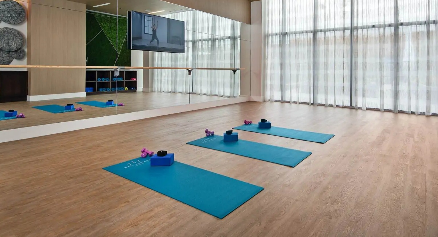 Bright yoga studio at 727 West Madison in Chicago with mirrored wall, barre, wood flooring, and mats set for quiet fitness classes