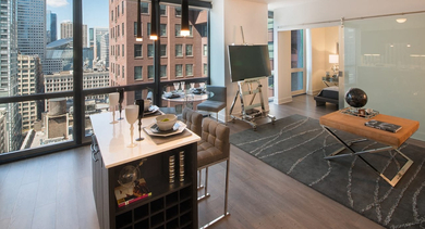 Open-concept living area with kitchen island, floor-to-ceiling windows, and city skyline views at 73 East Lake apartments in Chicago