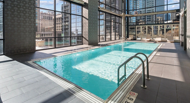 Bright indoor swimming pool surrounded by tall windows and city views at 73 East Lake apartments in Chicago