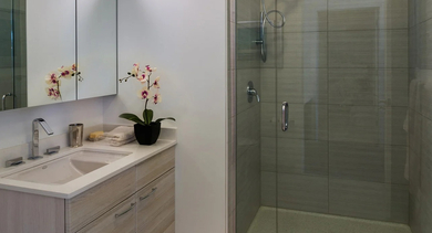 Modern bathroom with single vanity, mirrored cabinets, and a glass walk-in shower at 73 East Lake apartments in Chicago