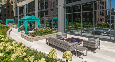 Outdoor lounge terrace with cabanas, modern seating, and garden planters at 73 East Lake apartments in Chicago's Loop