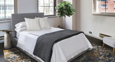 Bright, cozy bedroom at 731 Plymouth in Chicago featuring large industrial windows, a modern upholstered bed, and wood floors with area rug