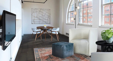 Spacious loft-style living and dining area at 731 Plymouth in Chicago, with arched windows, seating, wall-mounted TV, and sleek modern finishes