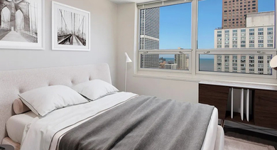 Bright bedroom with large windows showcasing lake and city views at 750 N Rush St apartments in River North, Chicago—ideal for renters seeking light-filled space
