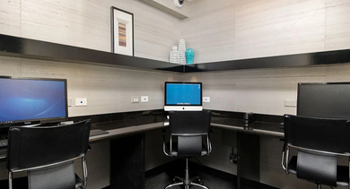 Resident business center with multiple computer stations, task chairs, and built-in counters at 750 N Rush St apartments in Chicago, convenient for work-from-home needs