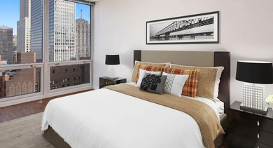 Cozy bedroom with modern decor, nightstands, and skyline view at 750 N Rush St apartments in River North, Chicago—great for renters wanting a relaxing retreat