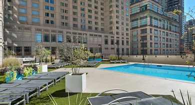 Landscaped rooftop sundeck with lounge chairs, greenery, and a large pool at 750 N Rush St apartments in Chicago, providing a relaxing outdoor escape with urban views
