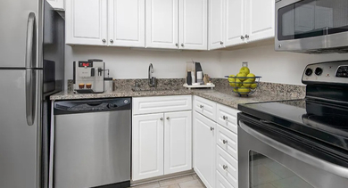 Modern U-shaped kitchen with white cabinets, granite counters, and stainless steel appliances at 750 N Rush St apartments in Chicago, perfect for everyday cooking