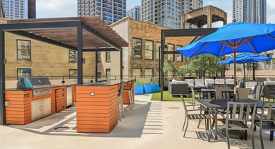 Outdoor amenity deck at 750 N Rush St in Chicago with BBQ grilling stations, shaded pergolas, patio tables, and lounge seating for summer gatherings