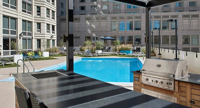 Outdoor kitchen with BBQ grill, sink, and counter space beside the rooftop pool at 750 N Rush St apartments in Chicago, ideal for summer cookouts and entertaining