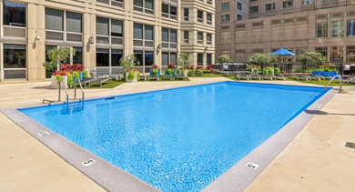 Sparkling outdoor swimming pool at 750 N Rush St in Chicago with spacious sundeck, lounge chairs, planters, and surrounding high-rise views