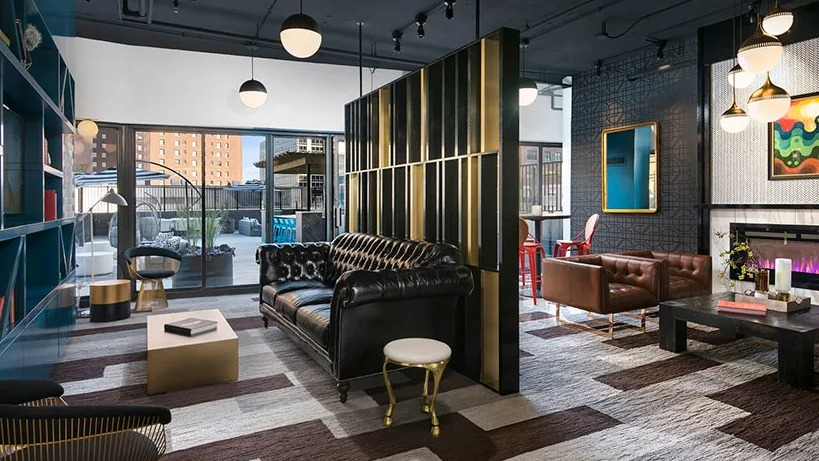 Upscale club room with library shelving, statement lighting, fireplace, and flexible seating beside terrace doors at 777 South State in Chicago