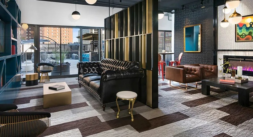 Upscale club room with library shelving, statement lighting, fireplace, and flexible seating beside terrace doors at 777 South State in Chicago