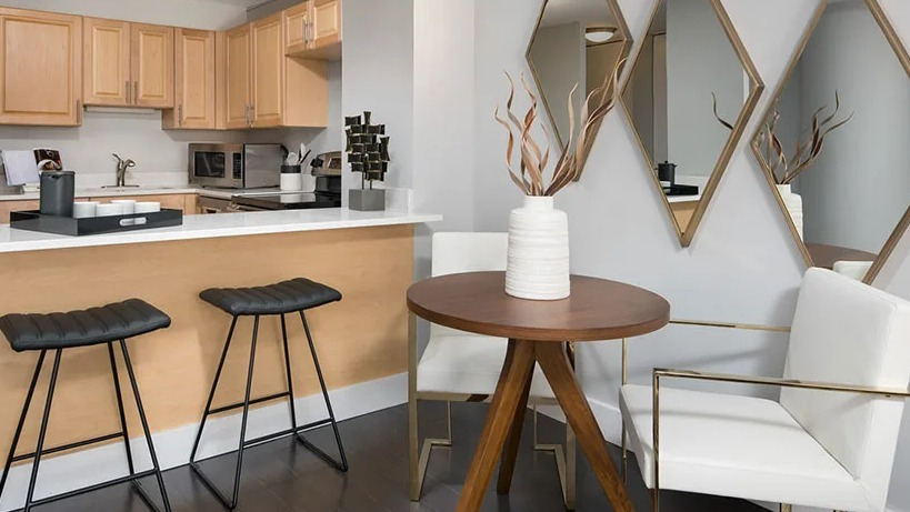 Dining nook with round table, bar seating, and mirrored accents beside a modern kitchen at 777 South State apartments in Chicago