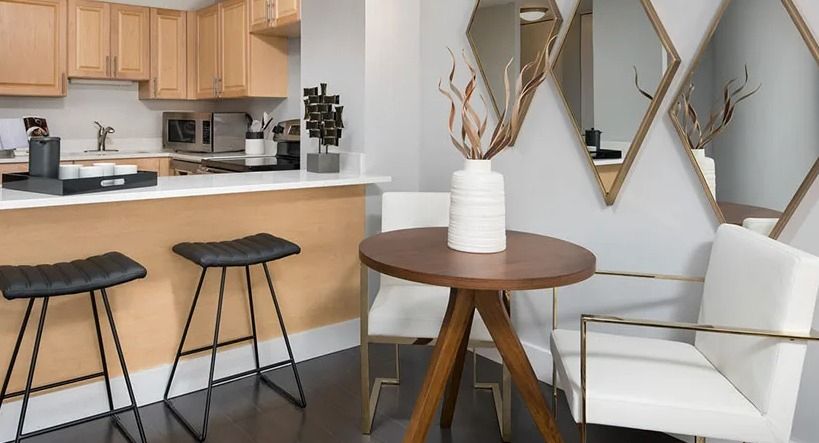 Dining nook with round table, bar seating, and mirrored accents beside a modern kitchen at 777 South State apartments in Chicago