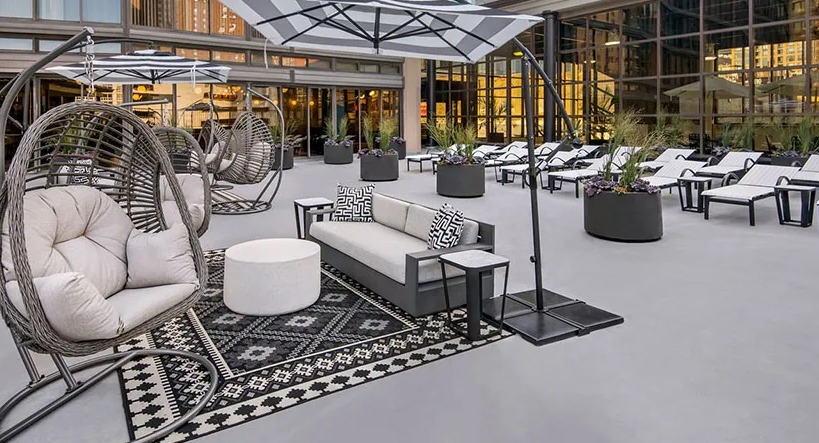 Relaxing outdoor lounge with hanging basket chairs, cushioned seating, and umbrellas on the terrace at 777 South State apartments in Chicago