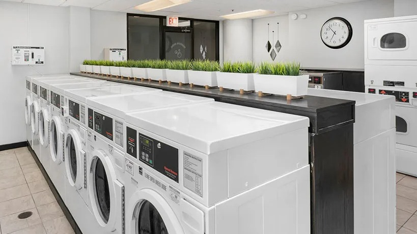 Community laundry room with rows of high-capacity washers and dryers, bright lighting, and clean tile floors at 777 South State in Chicago