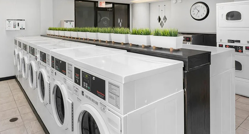Community laundry room with rows of high-capacity washers and dryers, bright lighting, and clean tile floors at 777 South State in Chicago